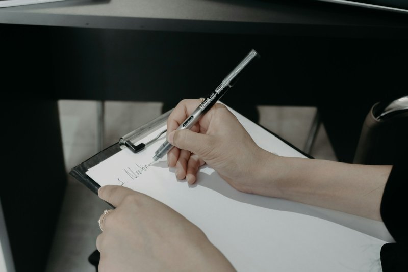 Professional planning how to write a sustainability plan for a DNP project on a clipboard