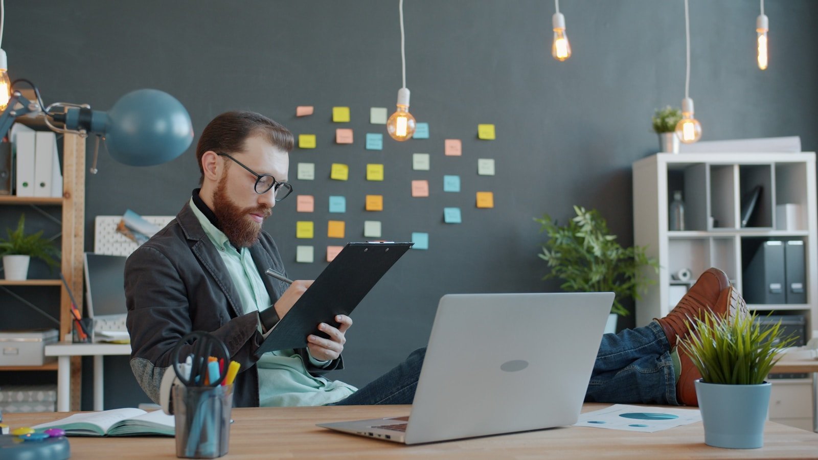 Professional reviewing a clipboard beside a laptop to use a graduate assignment rubric